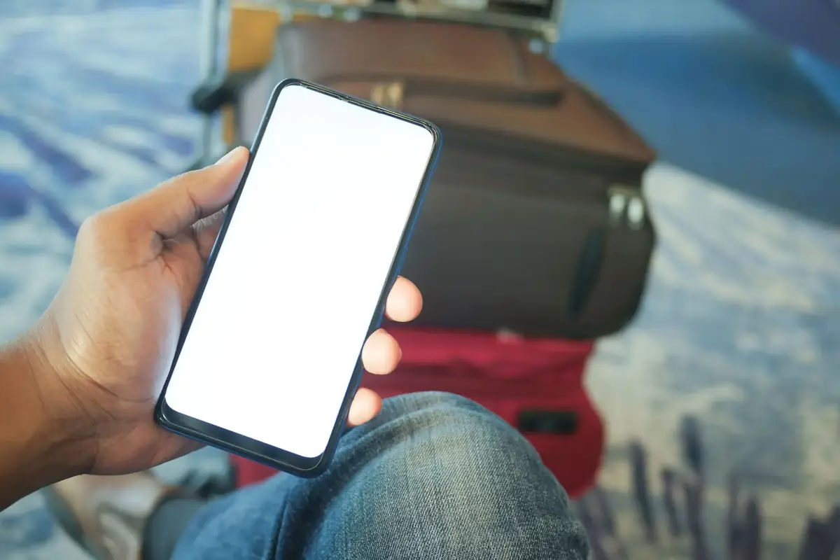 空港でスマートフォンを手にする旅行者